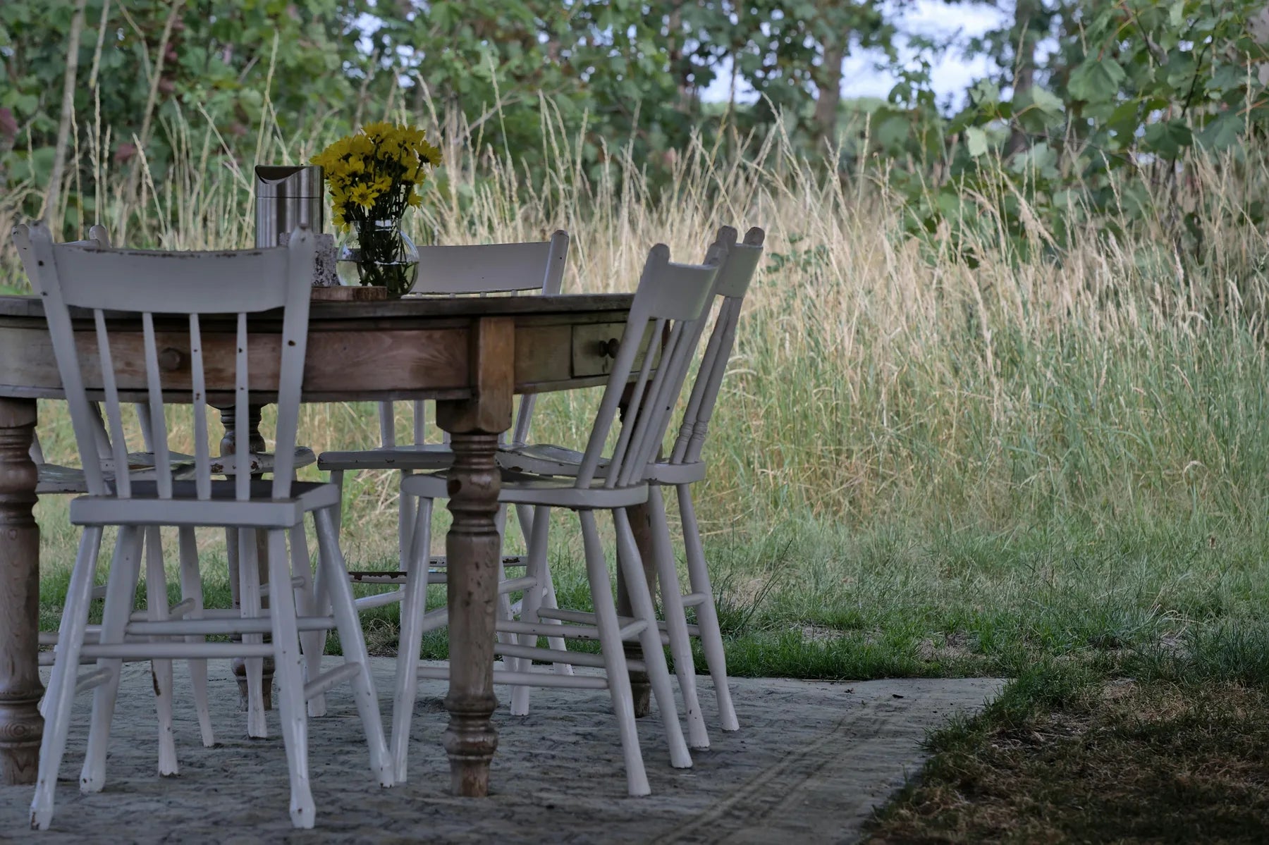De tafel staat klaar tussen het hoge gras — er is een stoel voor je